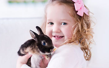 Little girl holding black, white and brown bunny