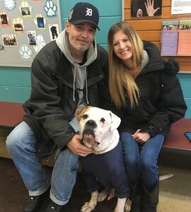 large white and brown dog posing for a picture with man and woman